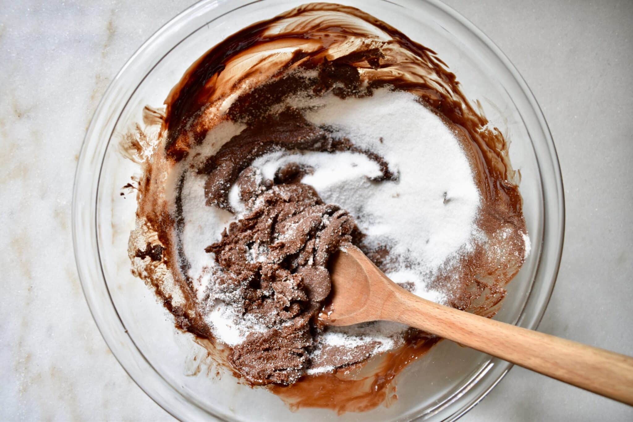 overhead shot of sugar being added to melted chocolate