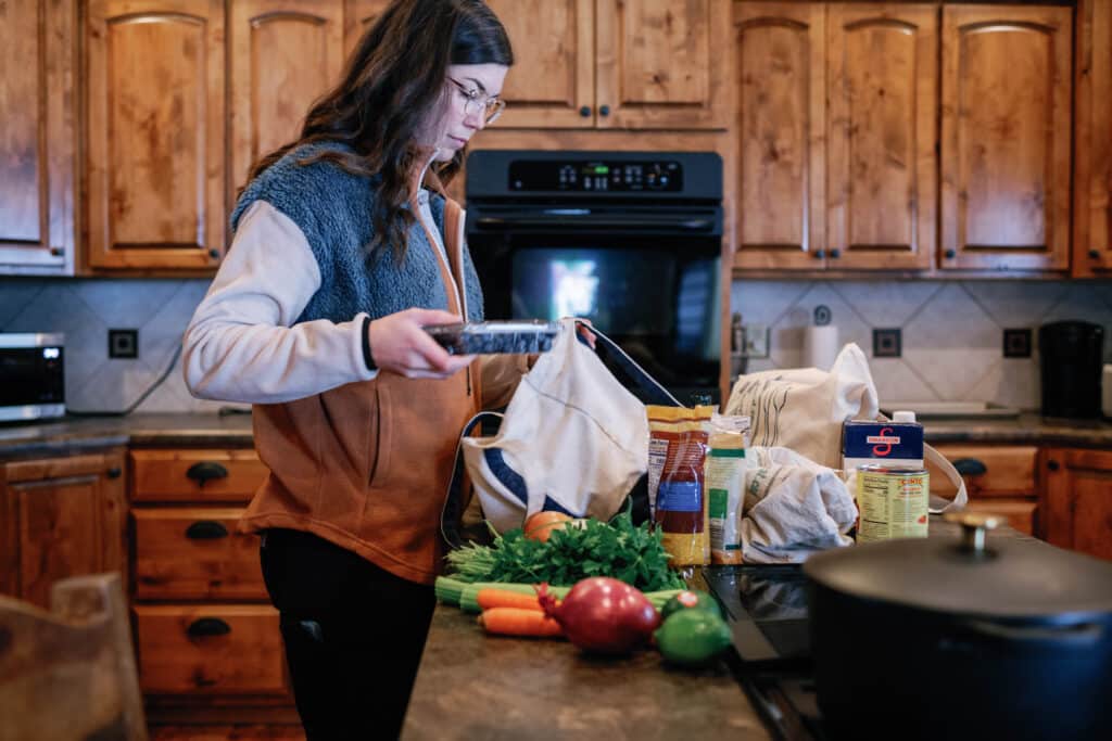 side view of a woman unloading groceries onto the kitchen counter