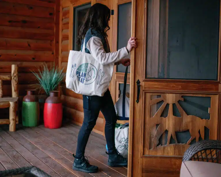 woman with a grocery bag on her shoulder opening the door to her house