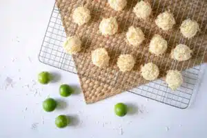 overhead image of macaroons on a cooling rack with limes scattered on the counter nearby