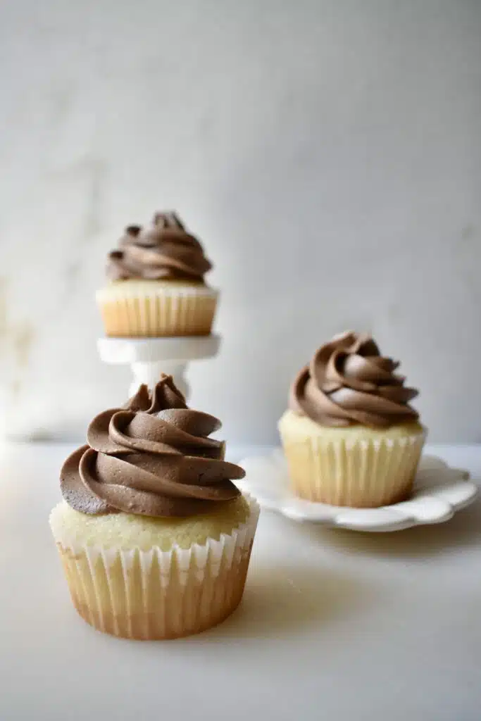 image of three vanilla cupcakes with chocolate frosting