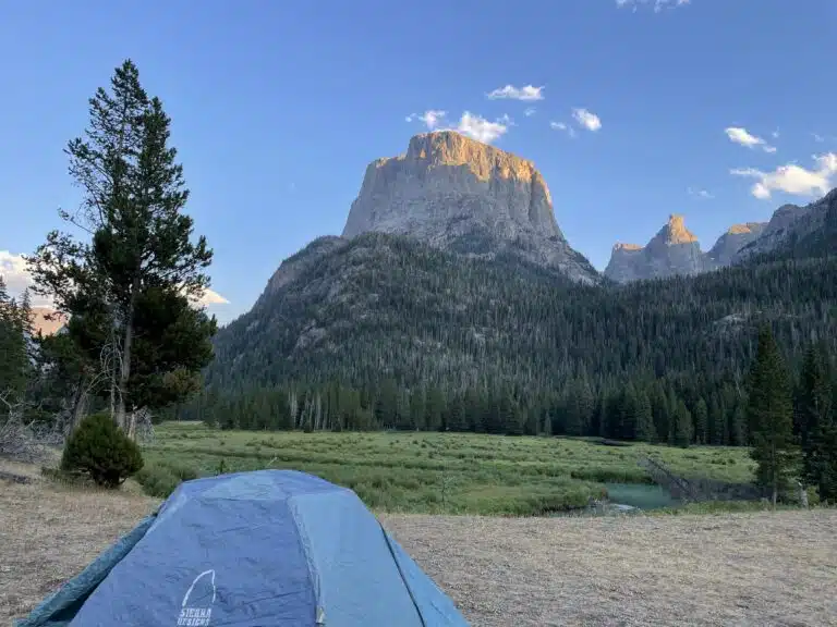 a blue tent setup in the grass with square top mountain in the distance