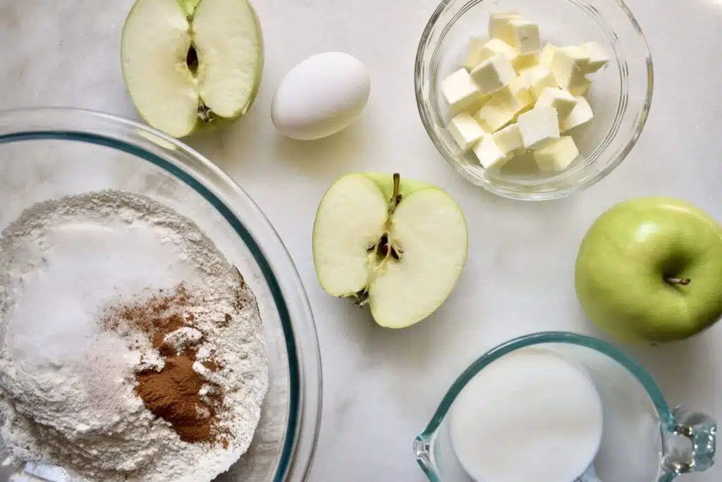 overhead shot of ingredients for cinnamon apple scones including butter, flour, and green apples