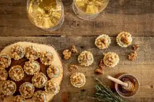 overhead shot of pear tartlets with two glasses of white wine on a wood board