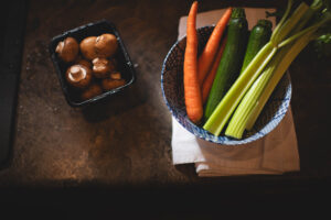 overhead view of two bowls of vegetables -carrots and celery in one and mushrooms in the other